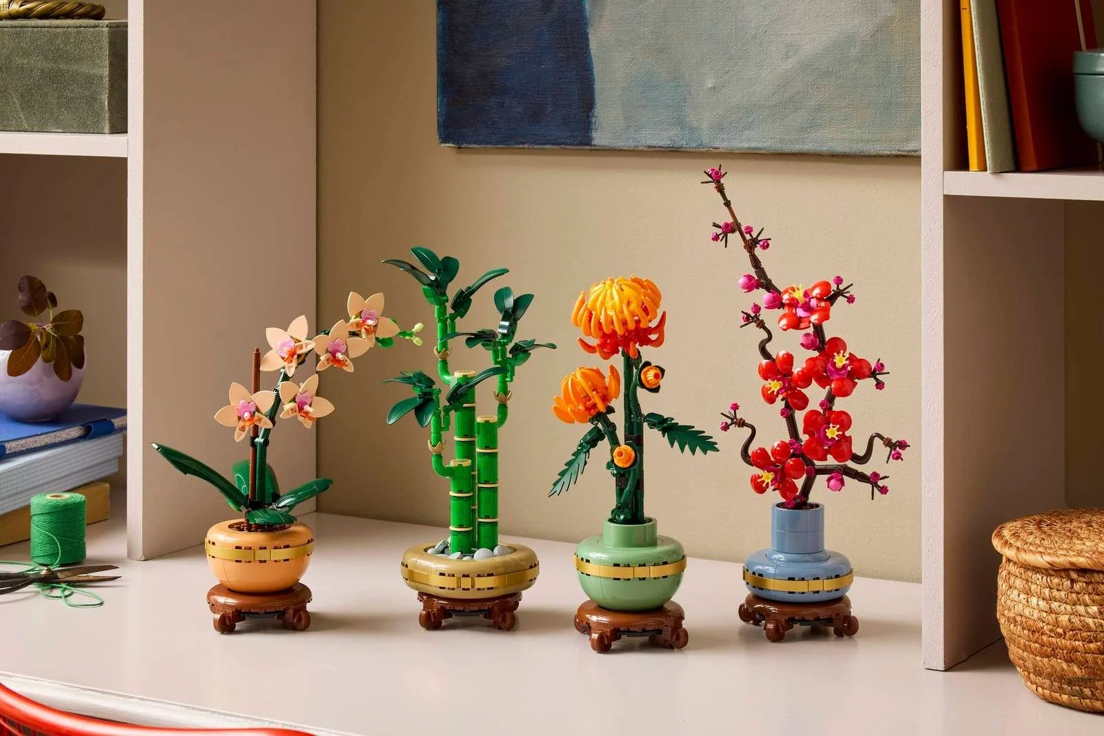 LEGO Mini Orchid, Lucky Bamboo, Chrysanthemum, and Plum Blossom sets displayed together on a desk