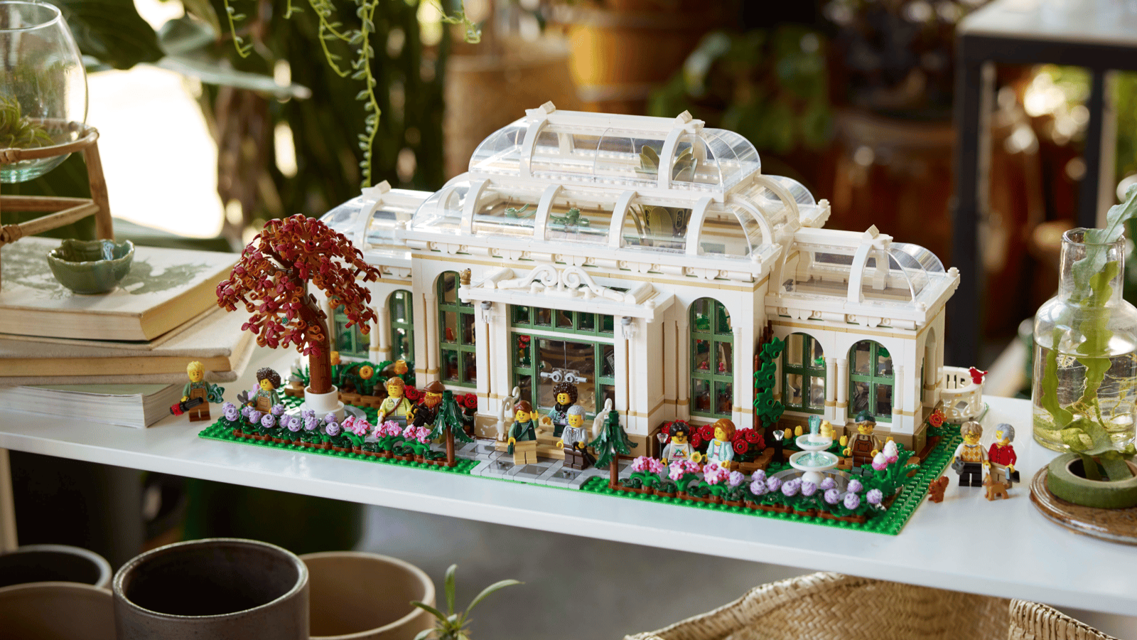 The LEGO Botanical Garden set on a shelf, its glass domed roof and garden minifigures surrounded by houseplants and books