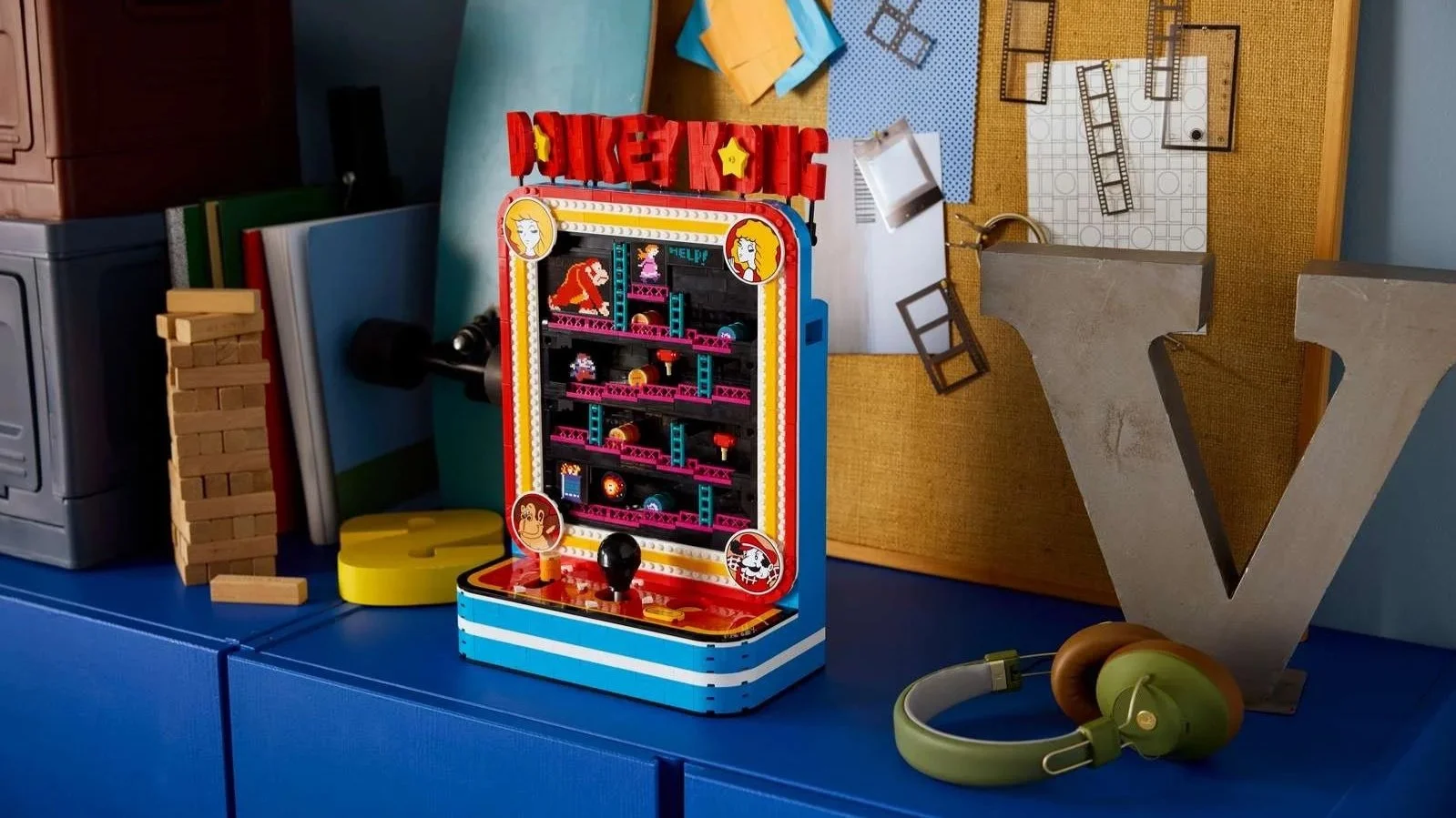 LEGO Donkey Kong Arcade machine on a blue dresser in front of a corkboard with pinned photos and film strips