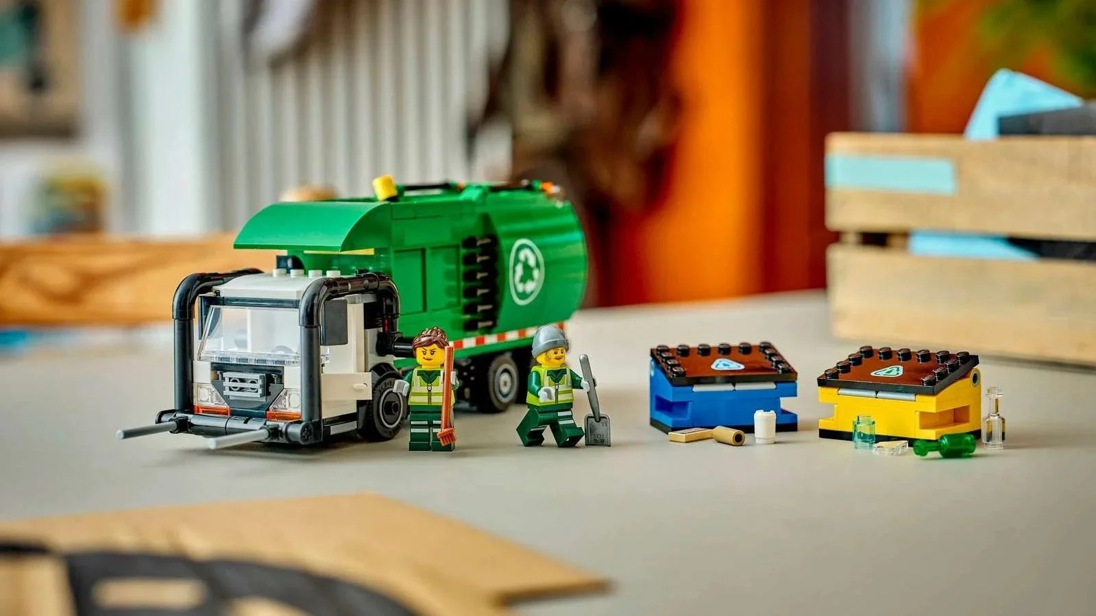 LEGO Recycling Truck with two minifigures in safety vests standing beside matching blue and yellow recycling bins on a desk