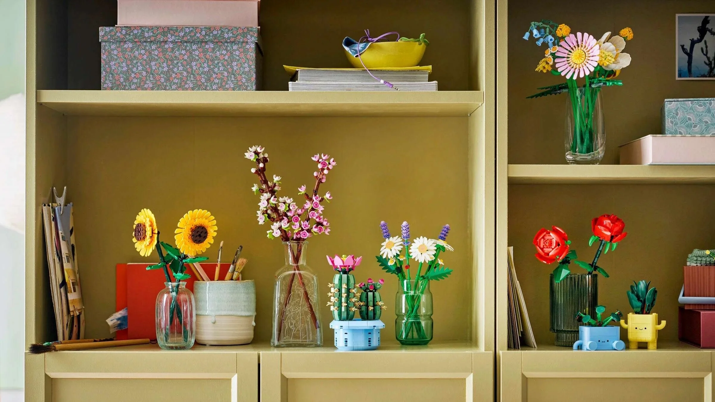 A collection of LEGO flower sets including sunflowers, cherry blossoms, cacti, and roses displayed on olive green shelves