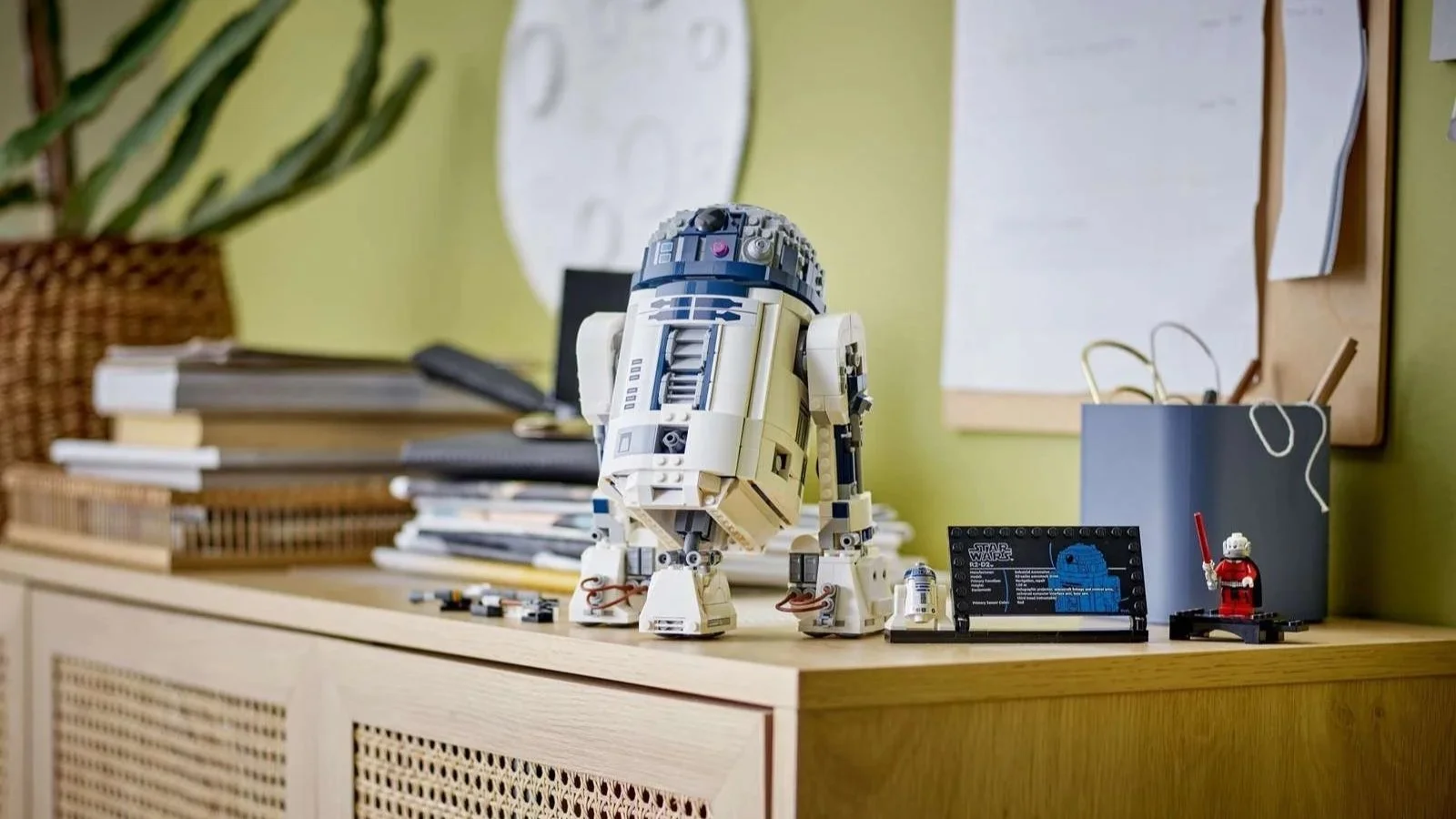LEGO Star Wars R2-D2 standing on a home office sideboard beside its info plaque and a mini droid figure