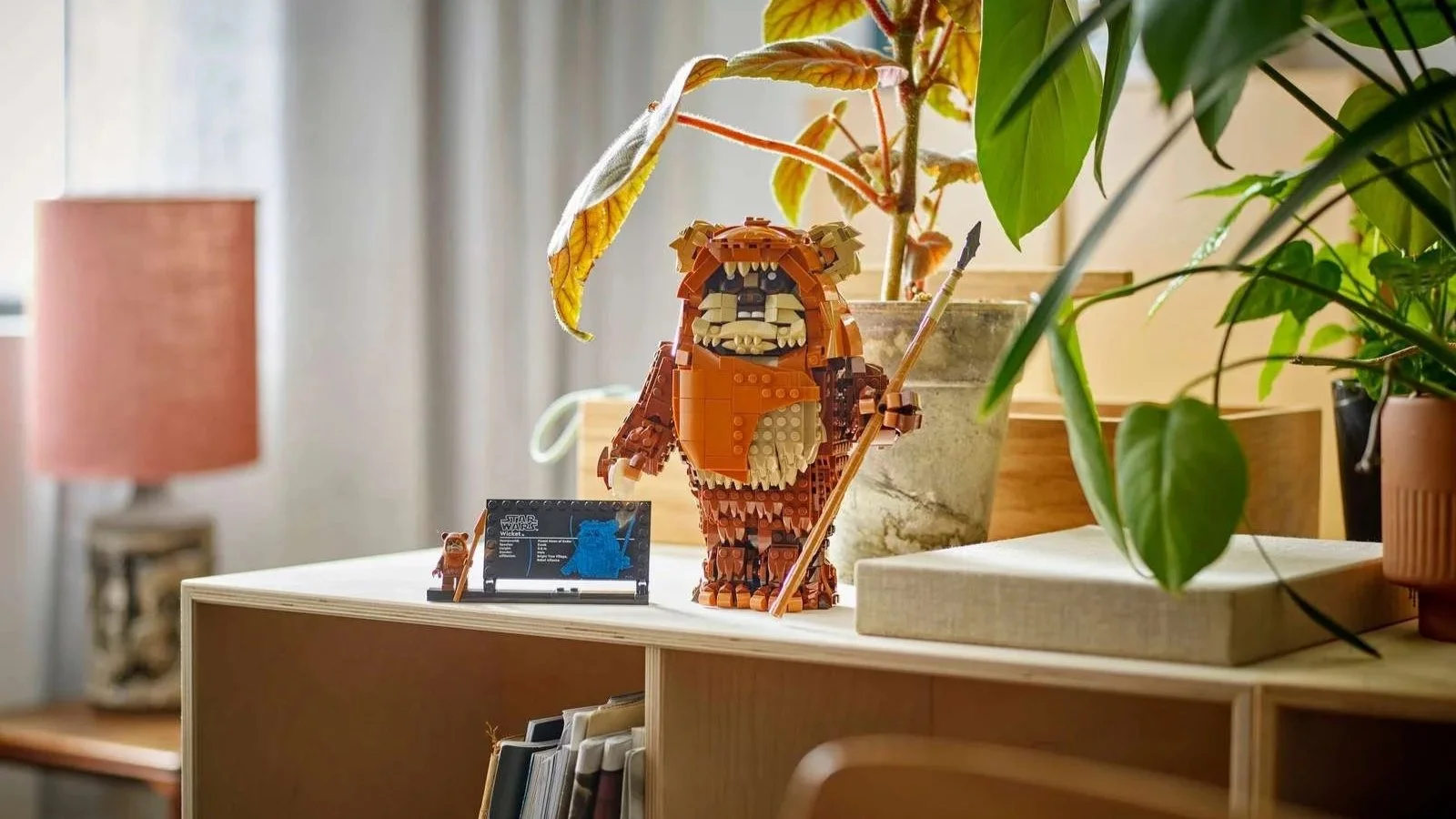 LEGO Star Wars Wicket the Ewok holding a spear on a plywood sideboard surrounded by potted houseplants