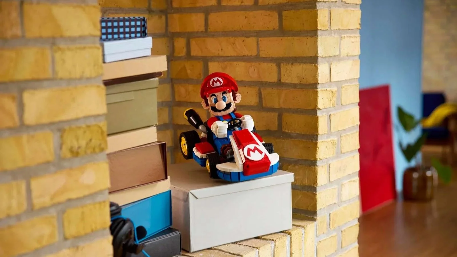 LEGO Mario Kart set with Mario driving the Standard Kart displayed on a stack of boxes between yellow brick pillars