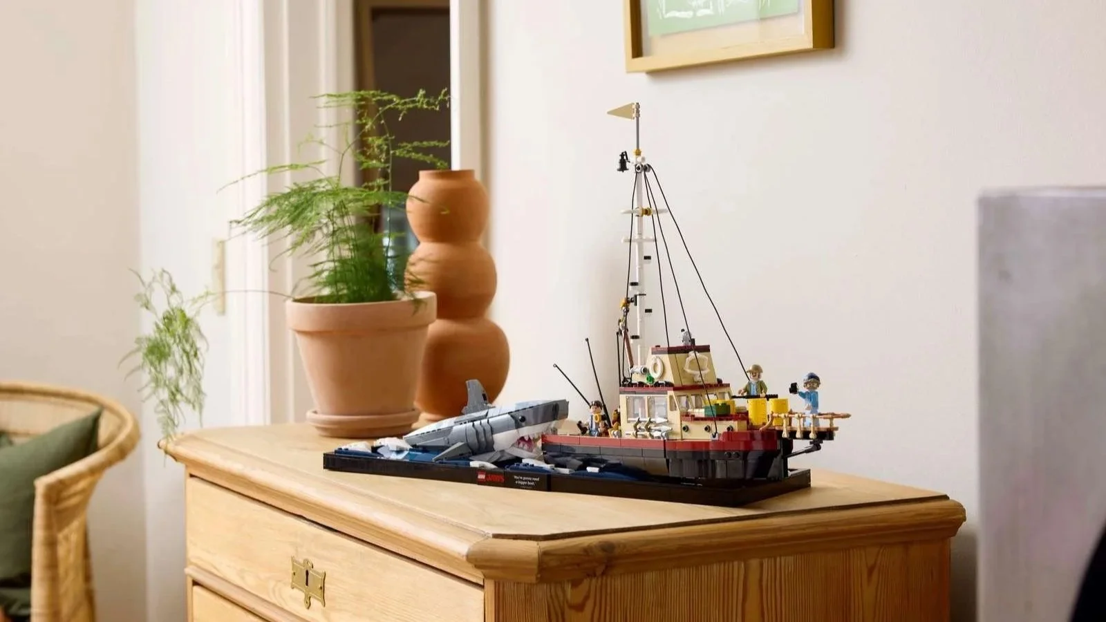 LEGO Jaws set with the shark and the Orca boat, displayed on a pine dresser beside a potted plant
