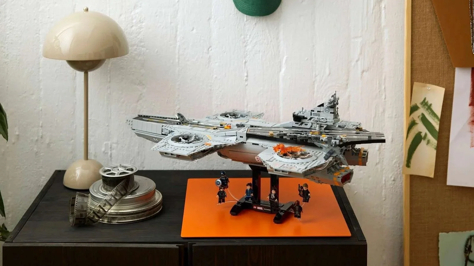 LEGO Marvel S.H.I.E.L.D. Helicarrier on a display stand on a dark cabinet beside a mushroom lamp and film reels