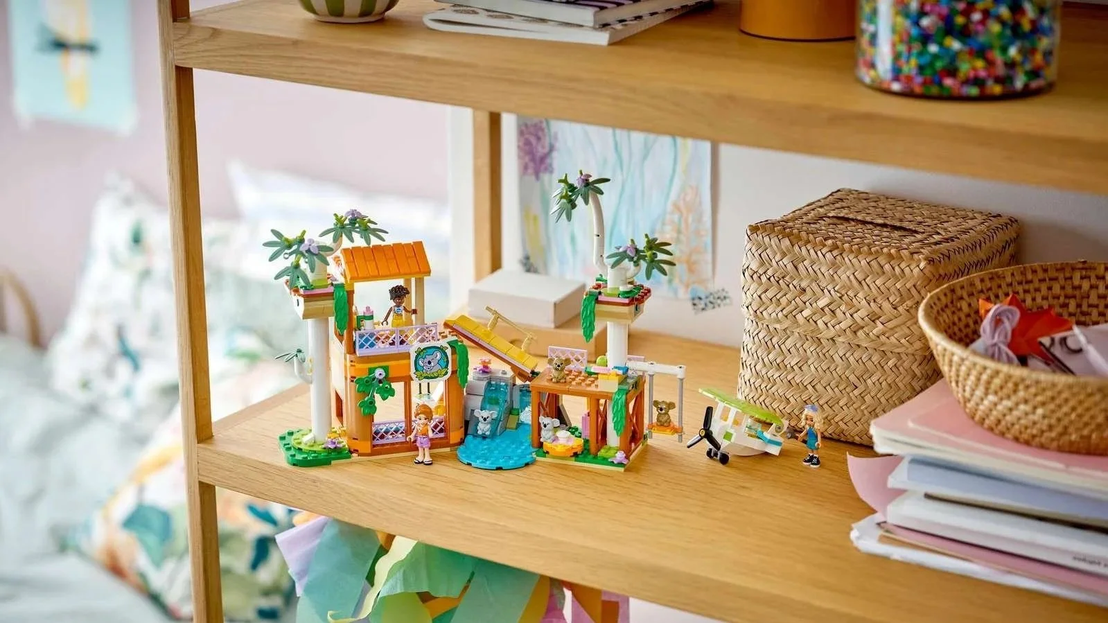 LEGO Koala Habitat and Care Center set on a wooden shelf, two orange treehouse-style buildings joined by a small waterfall, with koalas, a white seaplane and three figures