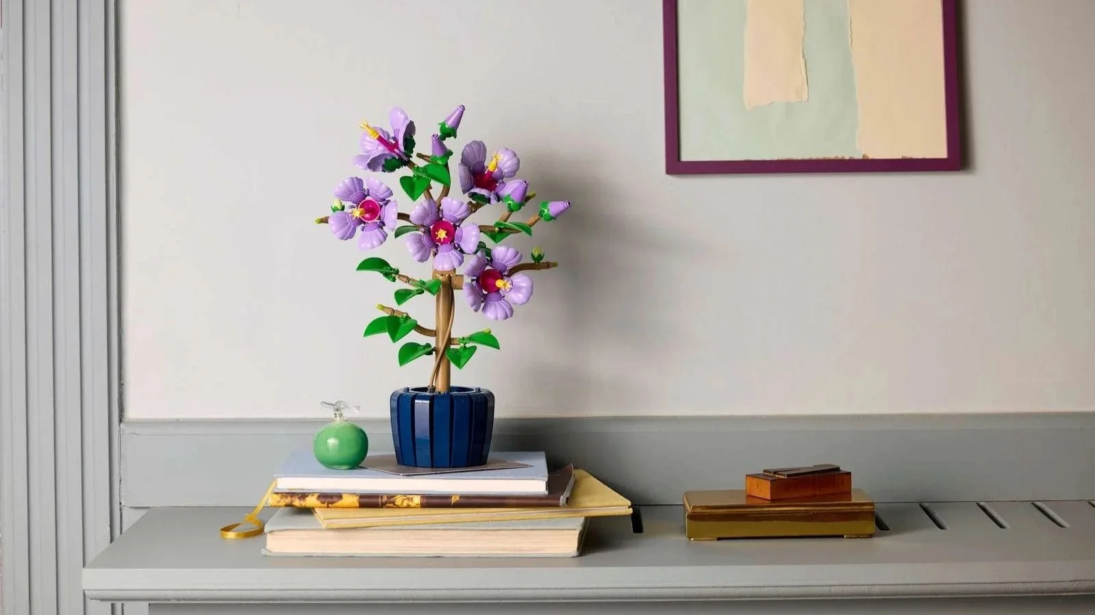 Hibiscus set with purple flowers in a navy pot displayed on a stack of books