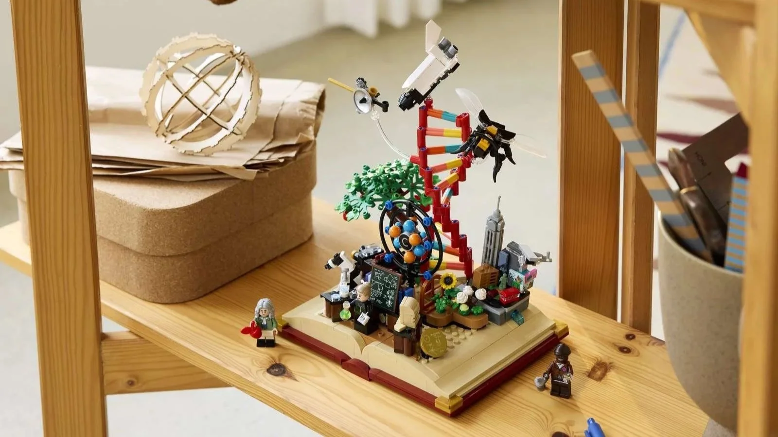 LEGO Evolution of STEM set on a wooden shelf, its storybook base rising into a DNA helix, satellite, and tiny city skyline