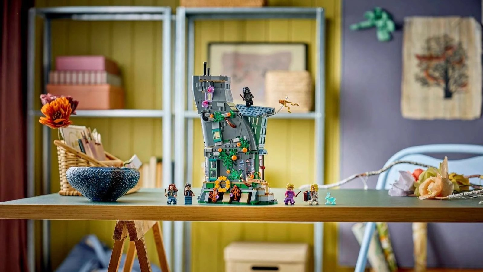 LEGO Luna Lovegood's House set, a tall leaning stone tower covered in green vines, with five minifigures and a glowing blue hare on a wooden desk