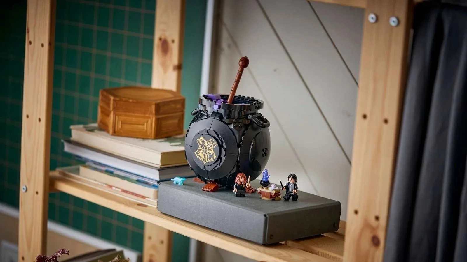LEGO Cauldron: Secret Potions Classroom set, a black cauldron with a gold Hogwarts crest and two minifigures, displayed on a wooden shelf