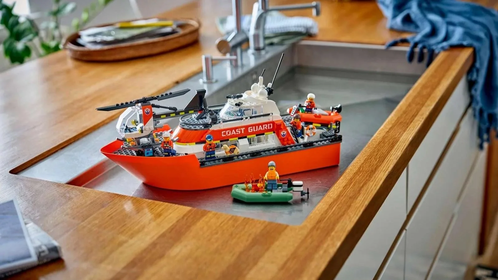 LEGO City Coast Guard rescue boat in orange and white with a helicopter, small rescue boats and minifigures on a kitchen counter