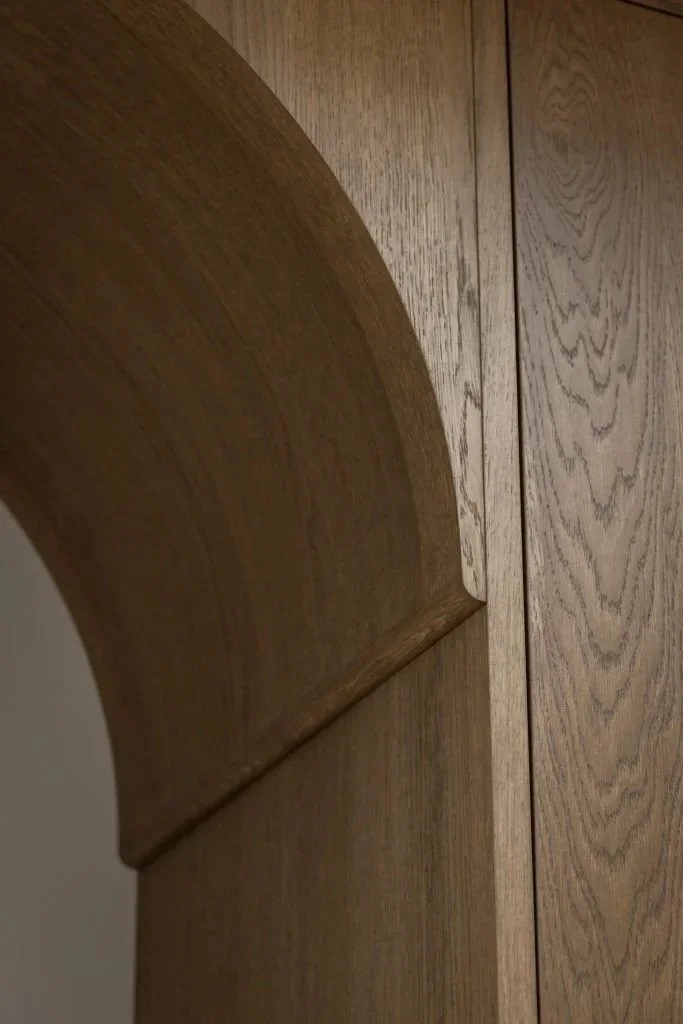 Close-up of a wooden cabinet with an arched design on the top corner.