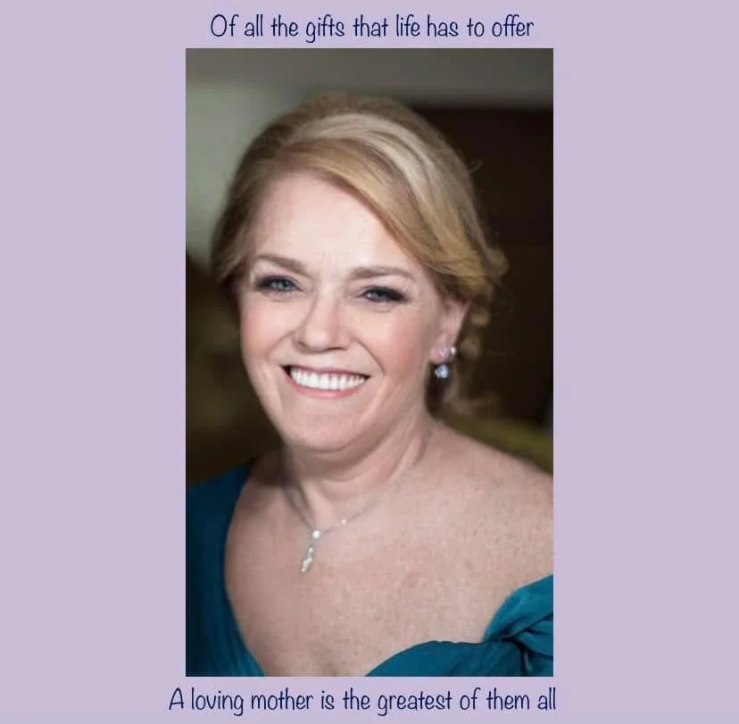 A smiling woman with light skin, blonde hair, and blue eyes, wearing a teal dress and jewelry, with a purple border featuring the quote "Of all the gifts that life has to offer, A loving mother is the greatest of them all".