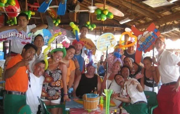 Group of people celebrating at a colorful party with balloons and decorations.