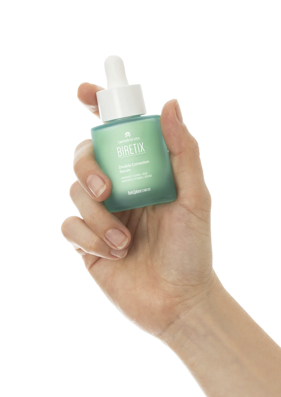 Hand holding a green bottle of Biretix Double Correction Serum with a white dropper cap against a white background.