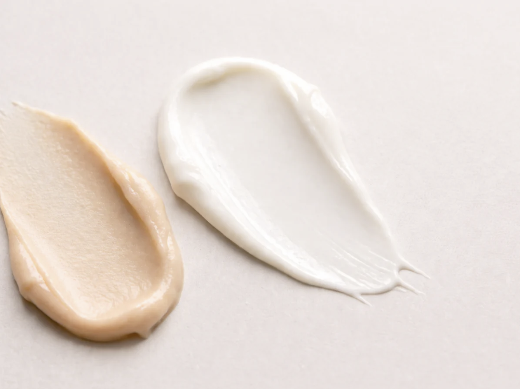 Close-up of mayonnaise and mustard sauces on a light-colored surface.