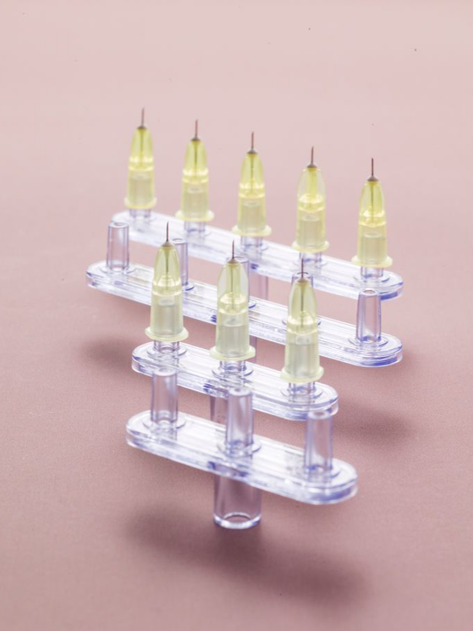 Close-up of a transparent medication blister pack with yellow-tinted ampules on a pink background.