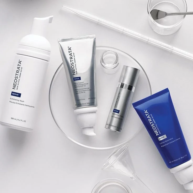 Collection of skincare products from Neostrata arranged on a clear glass plate and white surface, including a cleanser, exfoliating wash, moisturizer, and repair cream.