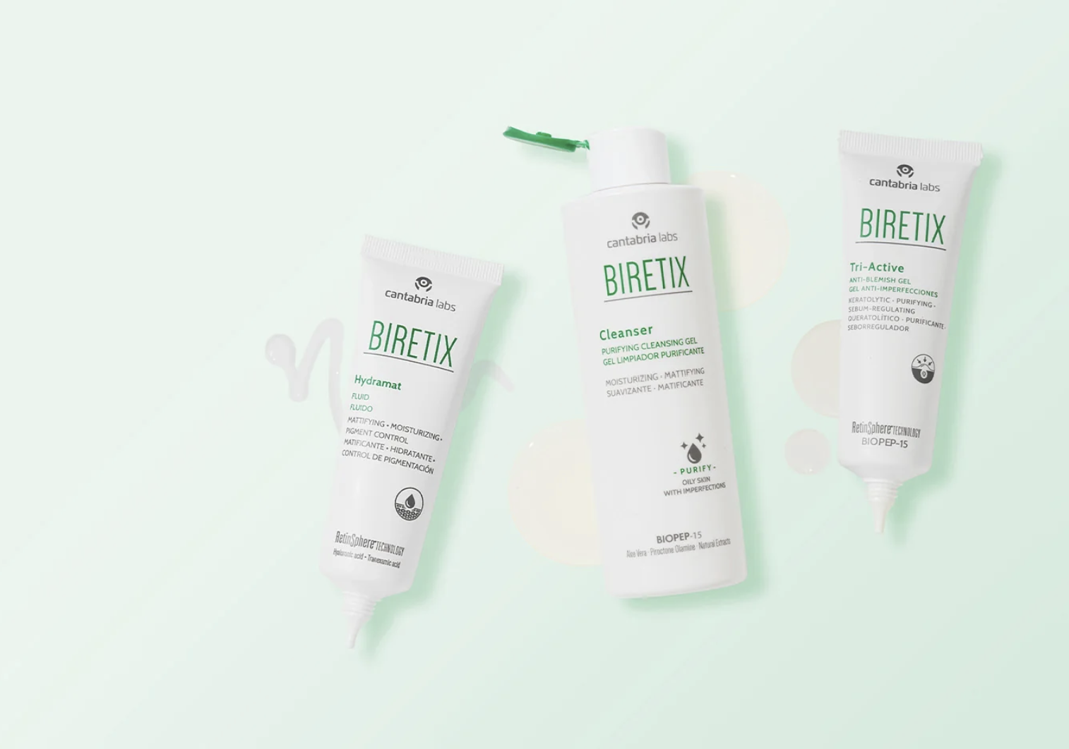 Three skincare products from the BIRETIX line by Cantabria Labs against a light mint green background. The products include a hydrating moisturizer, a purifying cleanser, and an anti-blemish gel.