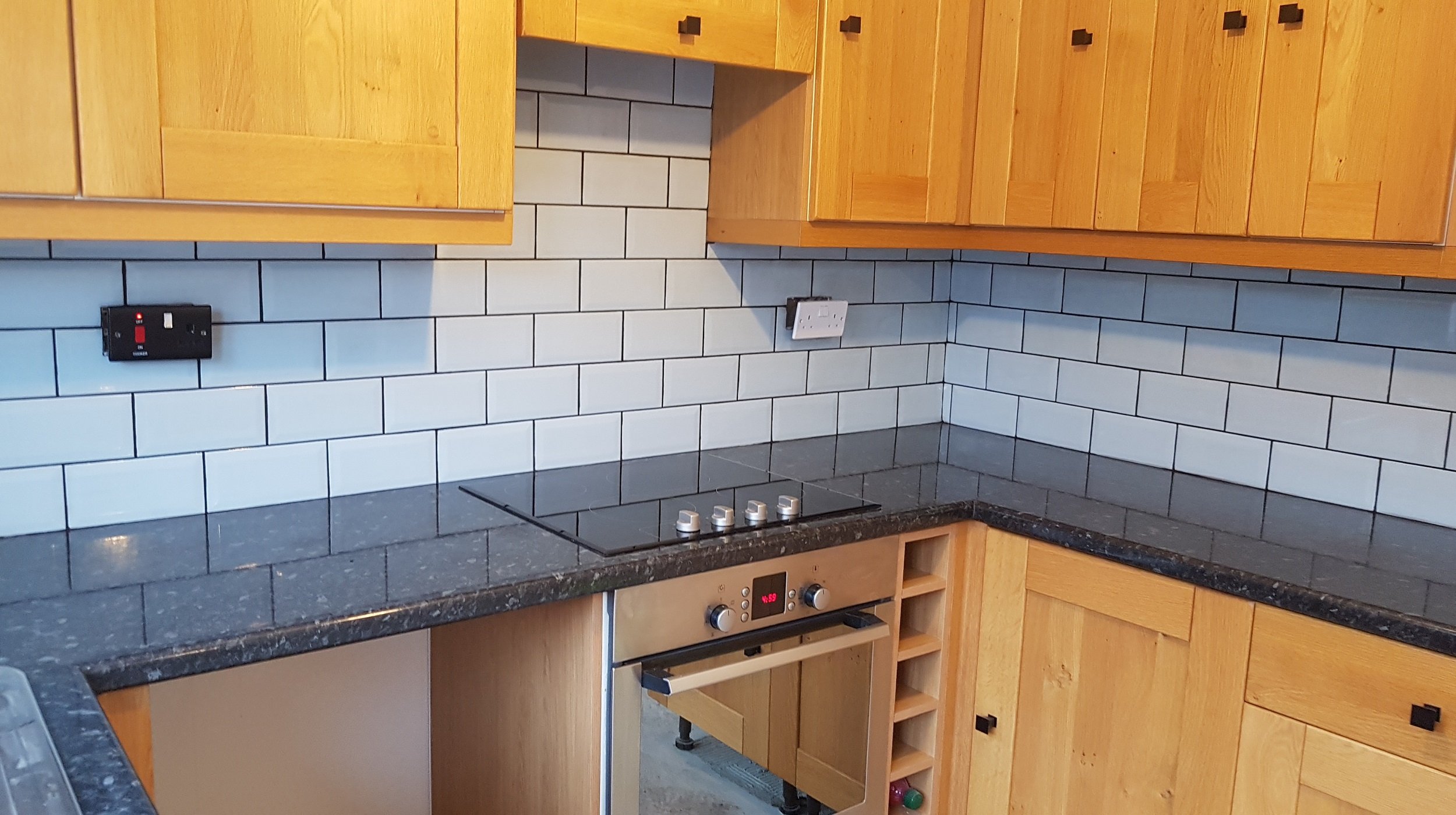 A kitchen refurbishments by Abbeydale Builders. With gloss worktops and shaker style doors, finished with a vibrant blue tiled splash back