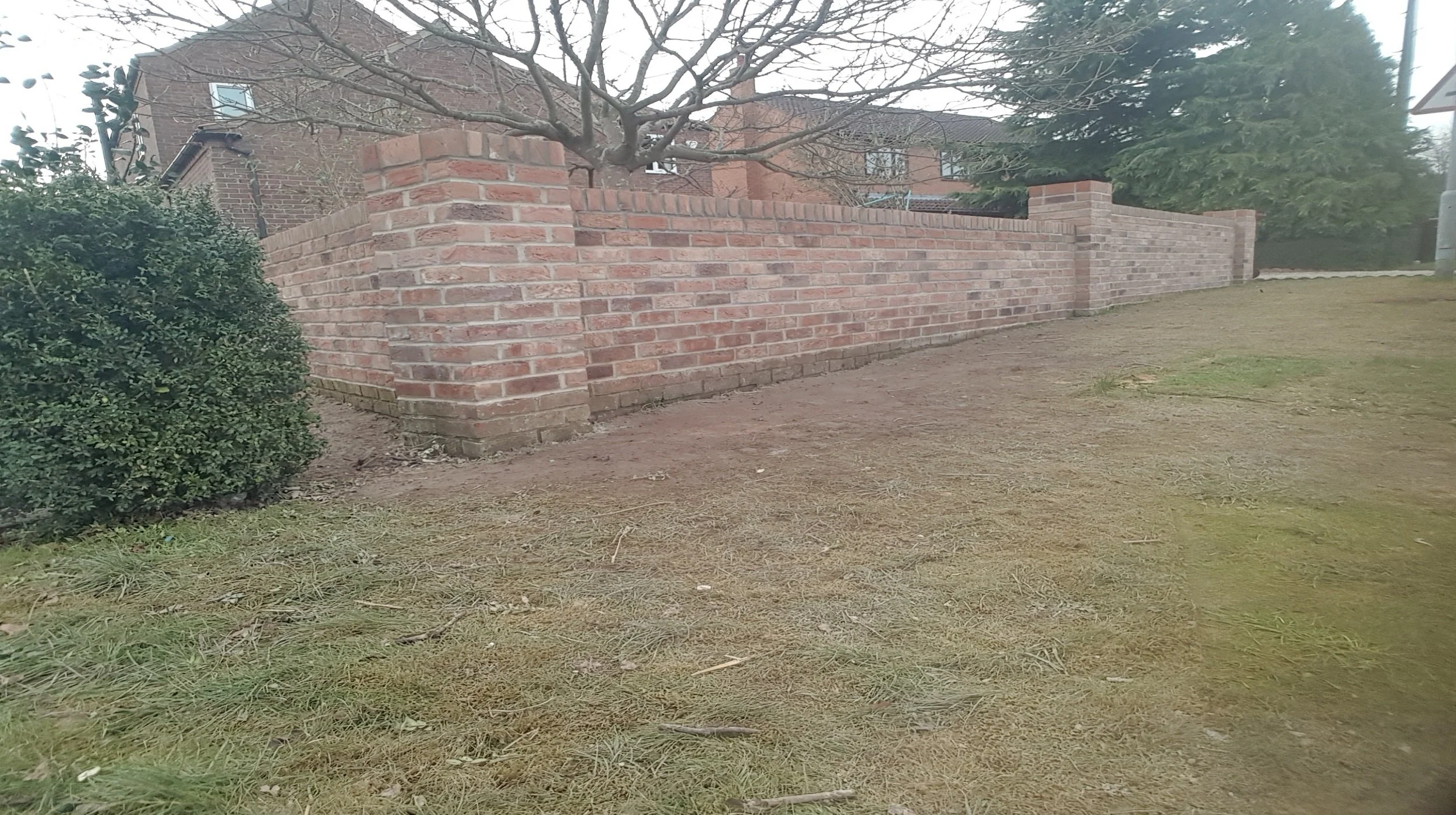 A long wrap around boundary wall built with reclaimed bricks
