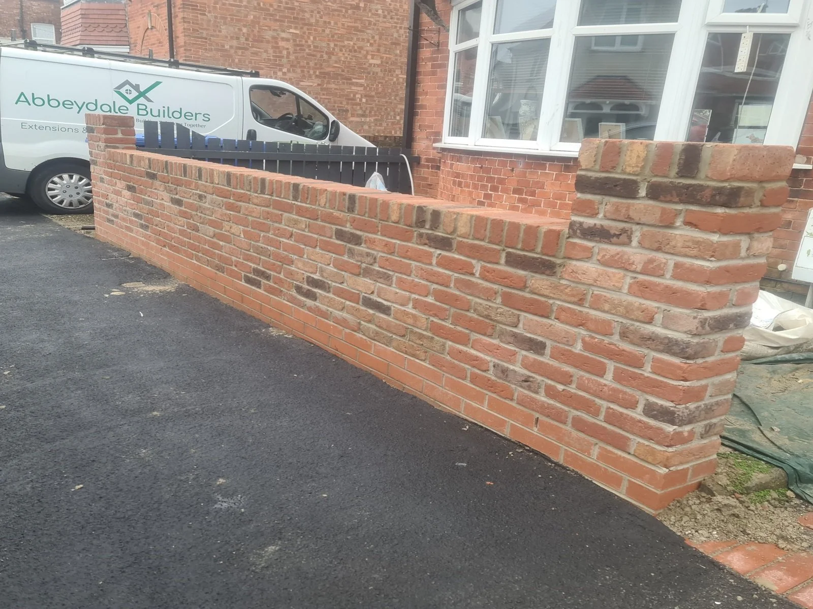 Newly built brick garden wall and pillar with Abbeydale Builders work van parked in the background.