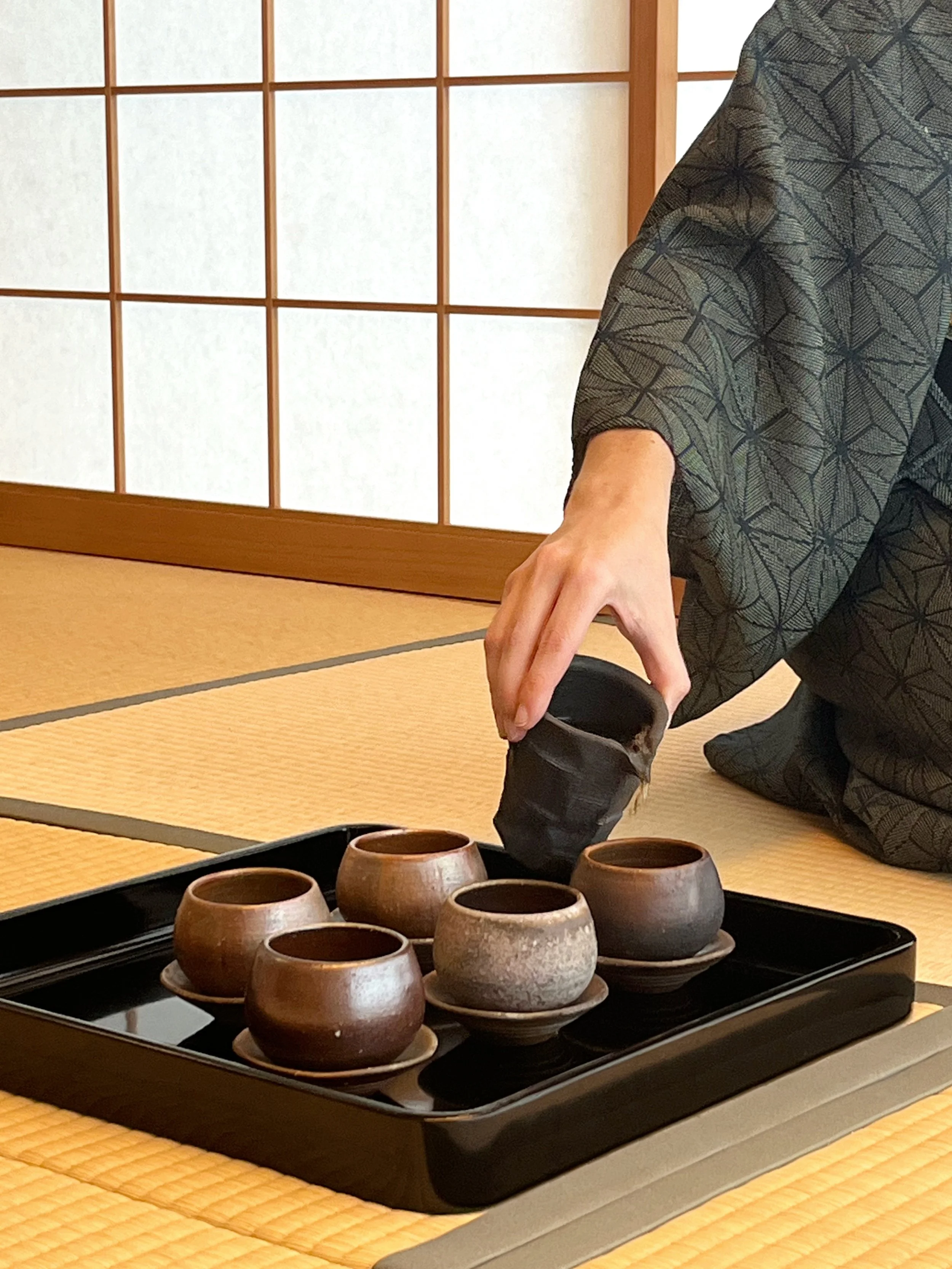 A tea ceremony setup on a tatami floor with cups made by Toshiaki Mori.