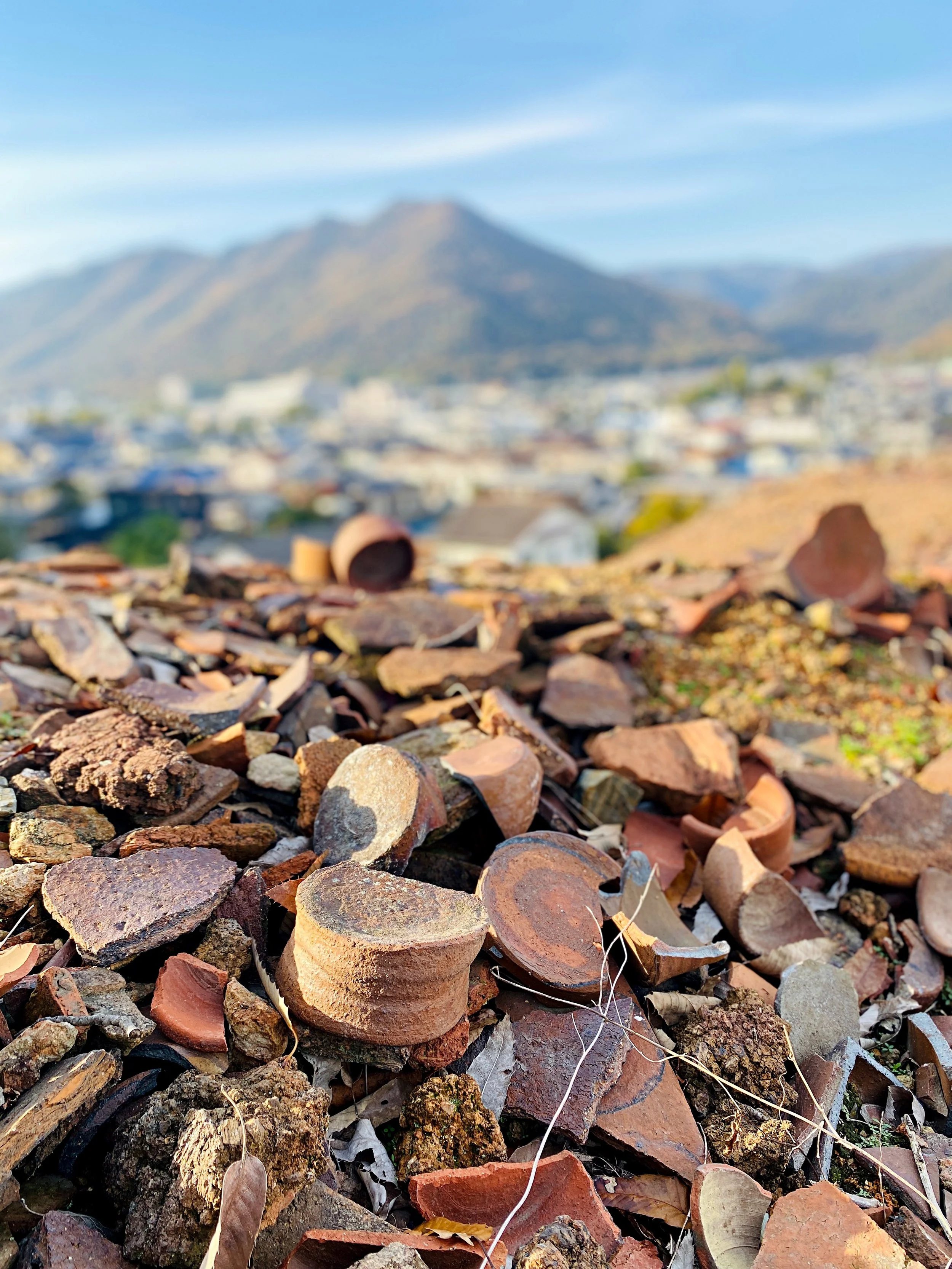 Old kiln site in Inbe, Bizen, where broken pottery pieces are scattered across the hillside above the town.