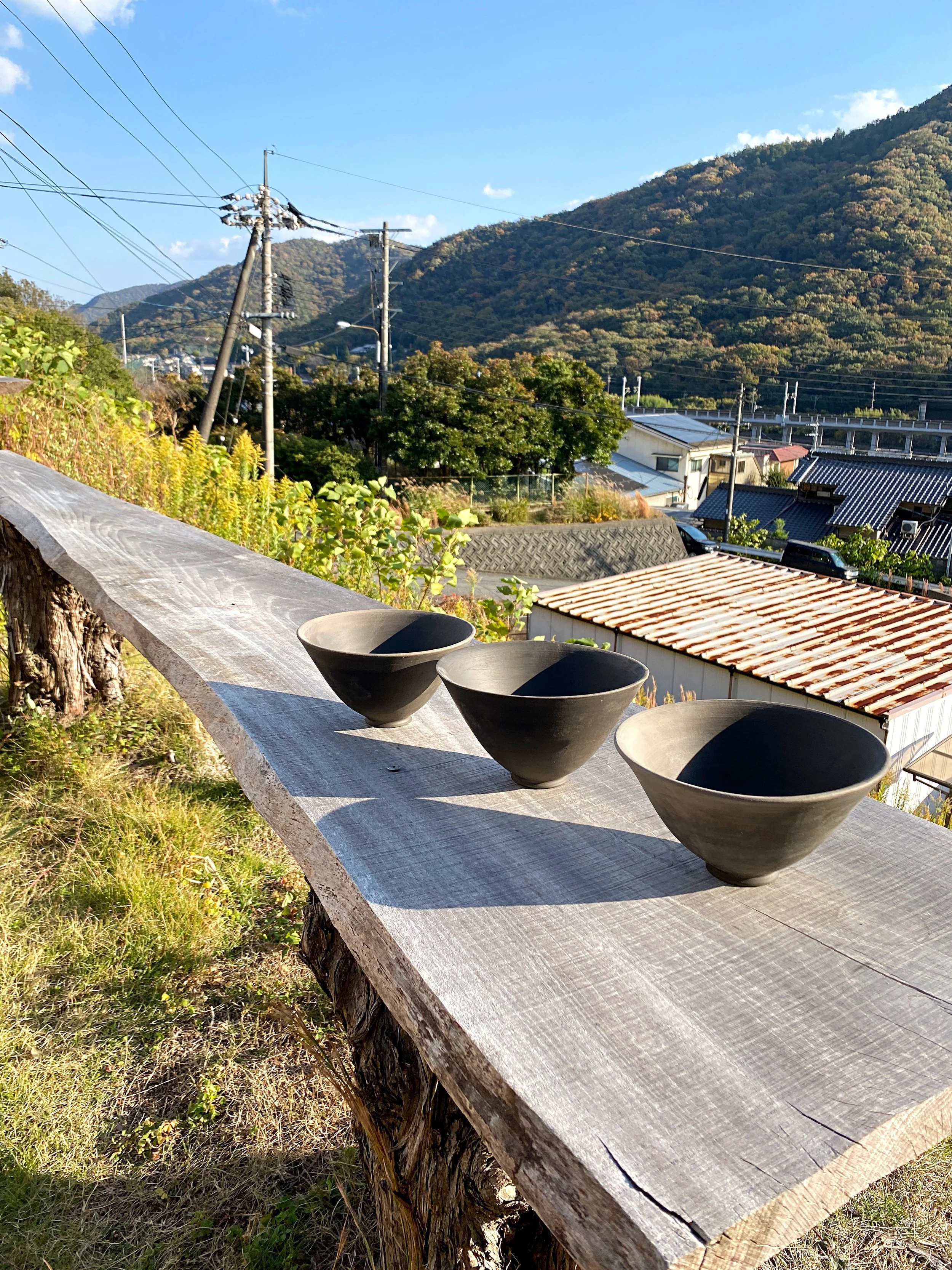 Freshly trimmed ramen bowls drying on a bench at Bizen Pottery Center, overlooking Inbe and the Shinkansen tracks.