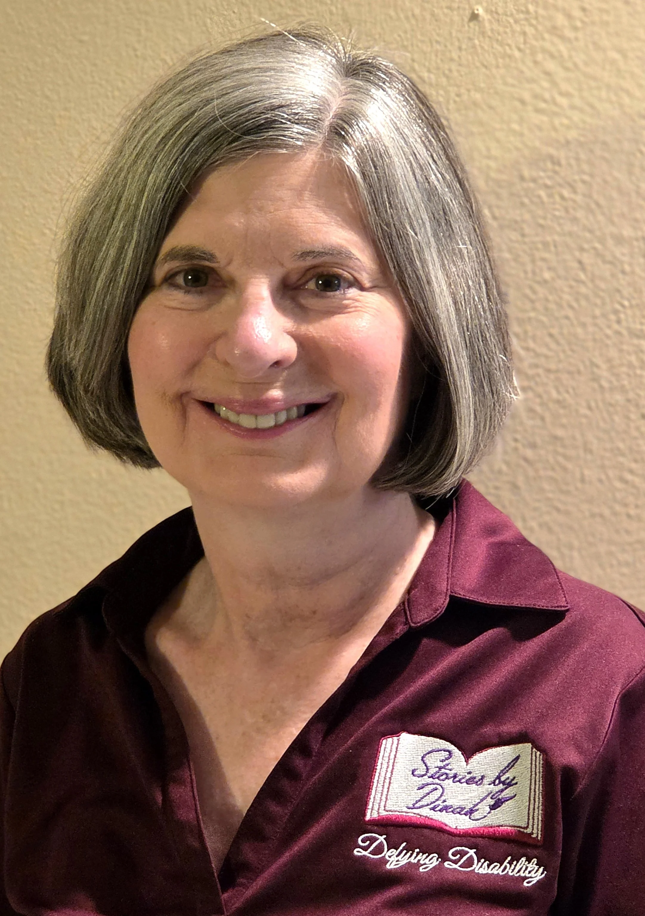 Author Dinah Jordan smiling in a burgundy shirt.