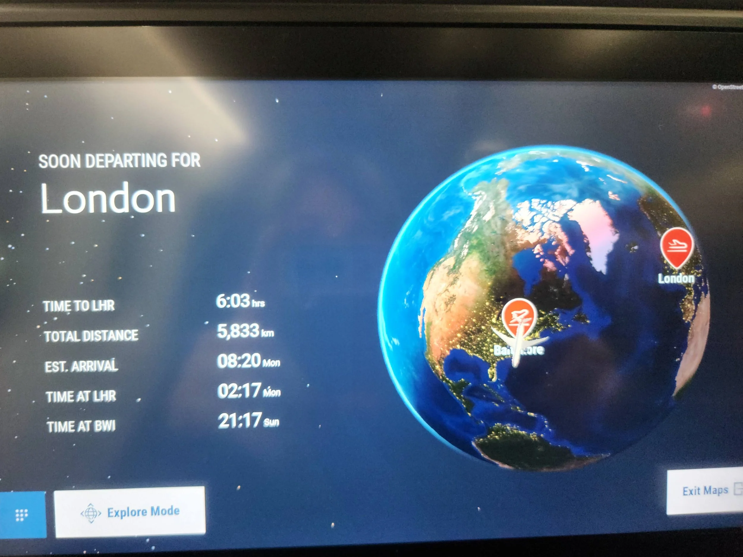 A seatback video monitor shows a digital map tracking an overnight flight from Baltimore to London, with route markers and flight details visible.