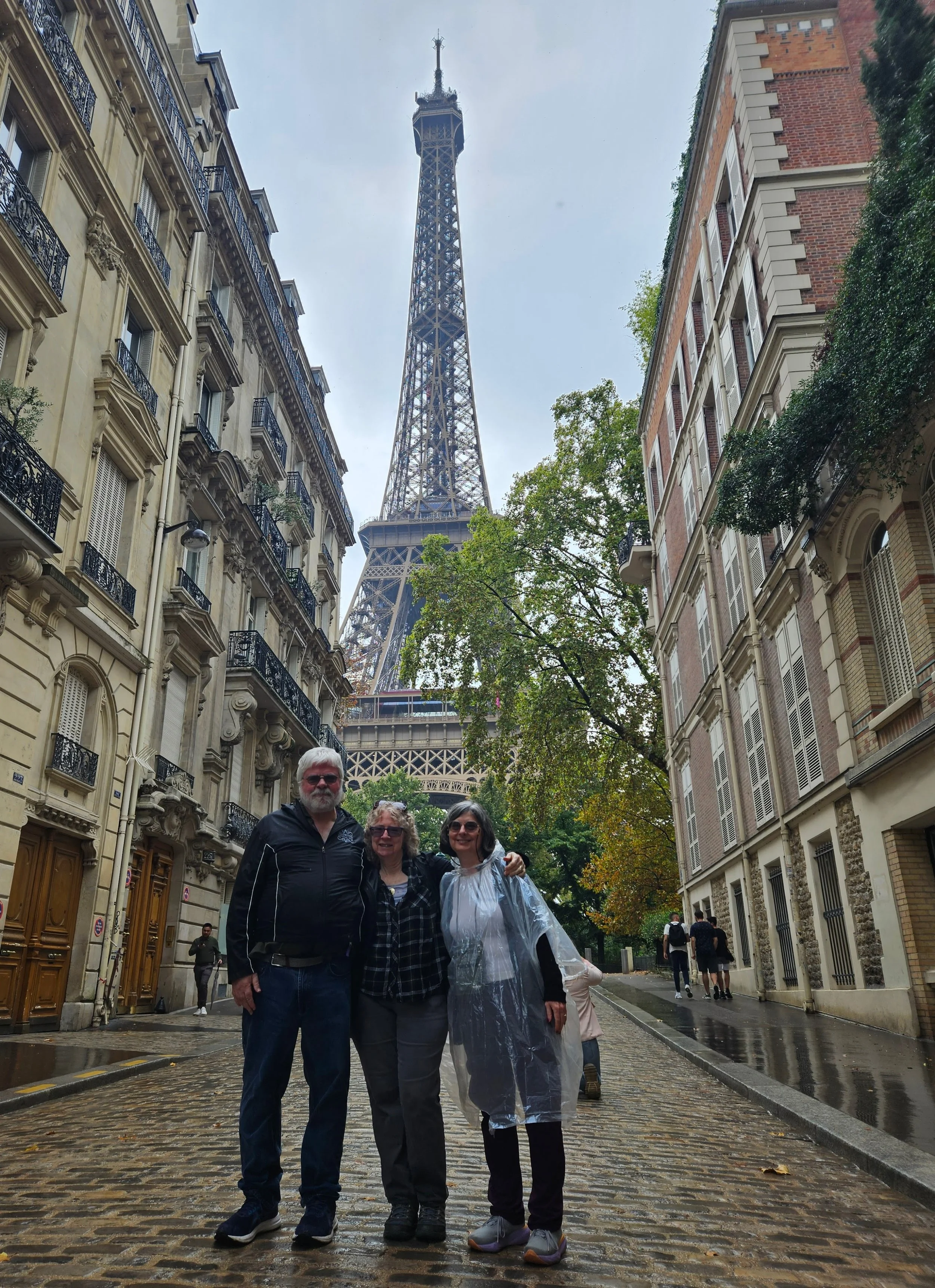 Dan, Donna, and Dinah stand on the street in front of the Eiffel Tower.