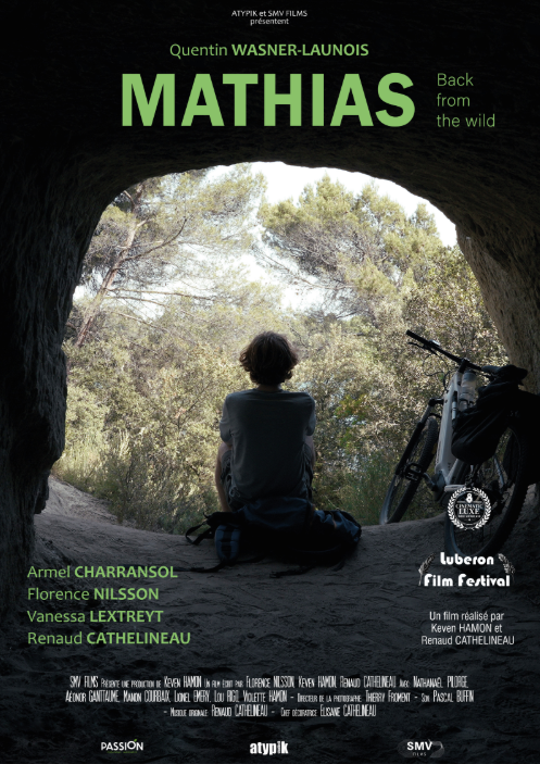 Une personne assise à l'entrée d'une grotte, regardant vers la nature avec des arbres et un vélo à côté. Titre du film : "Mathias" avec la mention "Back from the wild".