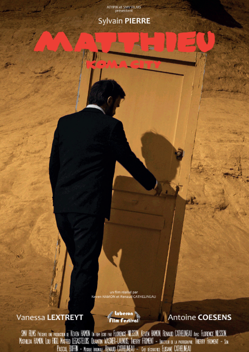 Affiche de film montrant un homme en costume noir ouvrant une porte dans un décor ressemblant à un désert ou un canyon, avec le titre en rouge "Mathieu" et le nom 'Komacity' écrit en rouge aussi.