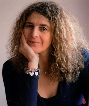 Portrait d'une femme aux cheveux bouclés, posant avec la main sous le visage.