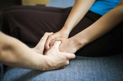 Person receiving comfort with hands being held from another person.