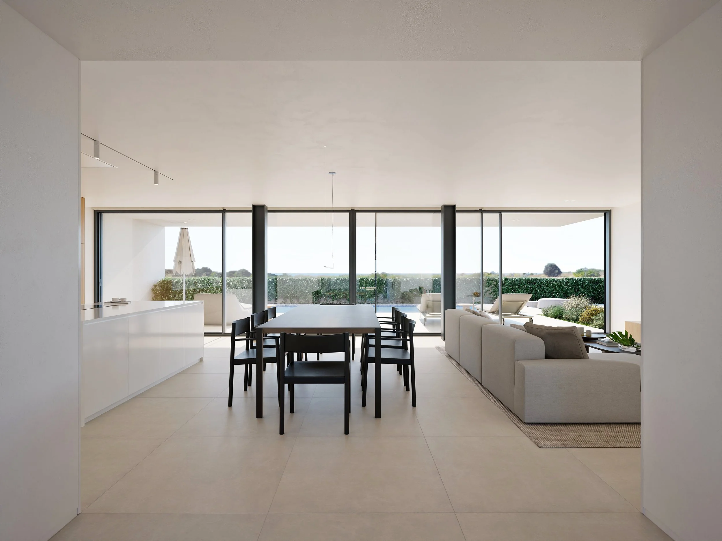 Modern interior living space with large floor-to-ceiling windows, a wooden dining table with black chairs, a white sofa, and outdoor patio furniture with a parasol, overlooking a green landscape.