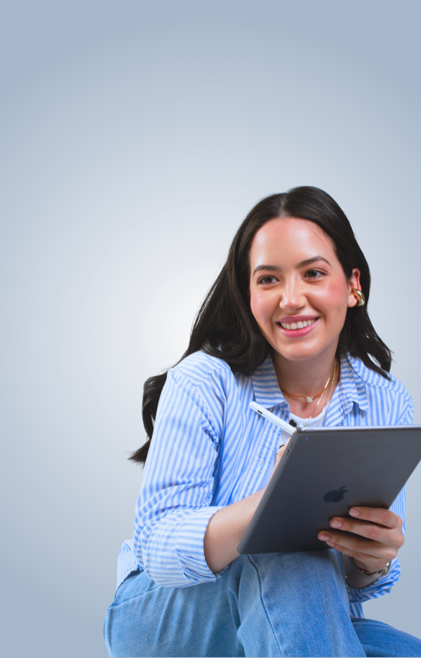 A young woman with long dark hair, wearing a blue striped shirt and jeans, is smiling and holding a tablet and stylus against a plain light blue background.