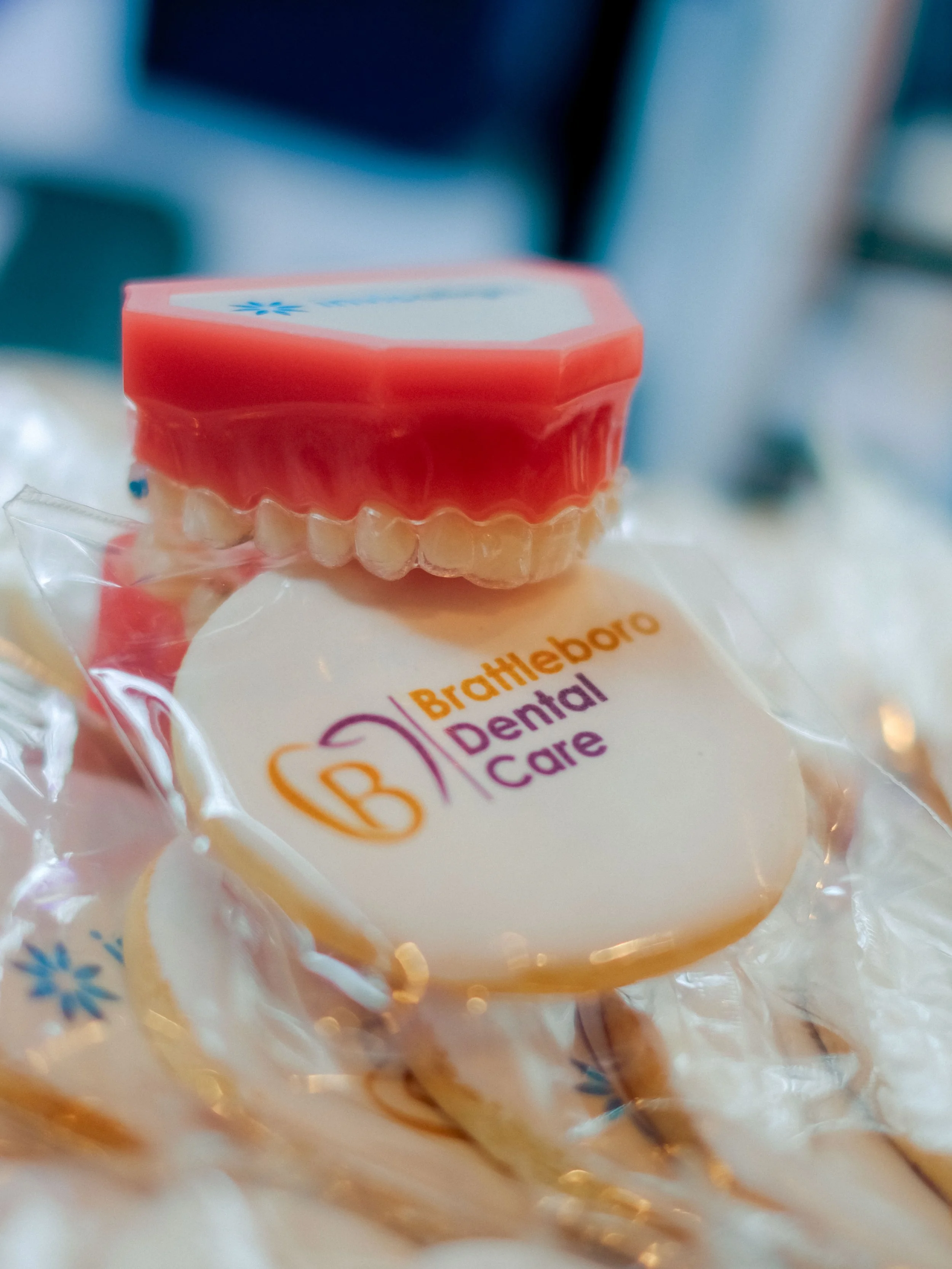 A set of dental prosthetics including a pink gum-colored base and white teeth, partially wrapped in clear plastic packaging with a label that reads "BrightWhite Dental Care," resting on a surface.