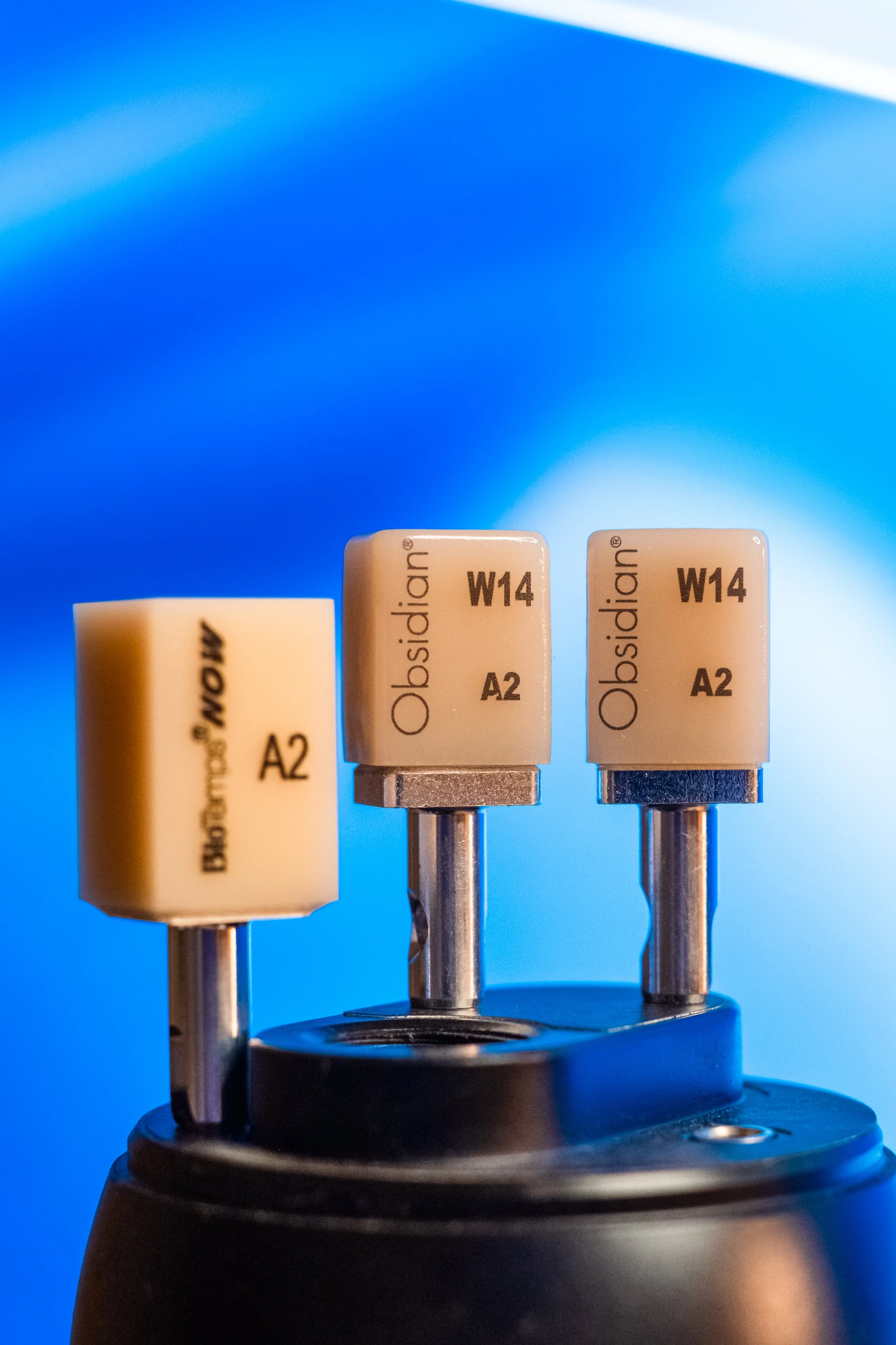Close-up of a microscope objective lens with labels 'Obsidian W14 A2' against a blue background.