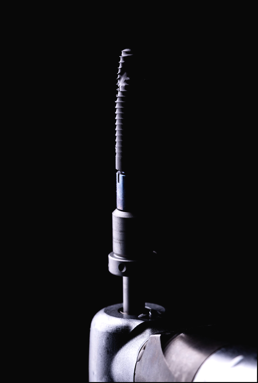 Close-up of a metallic medical or industrial tool against a black background.