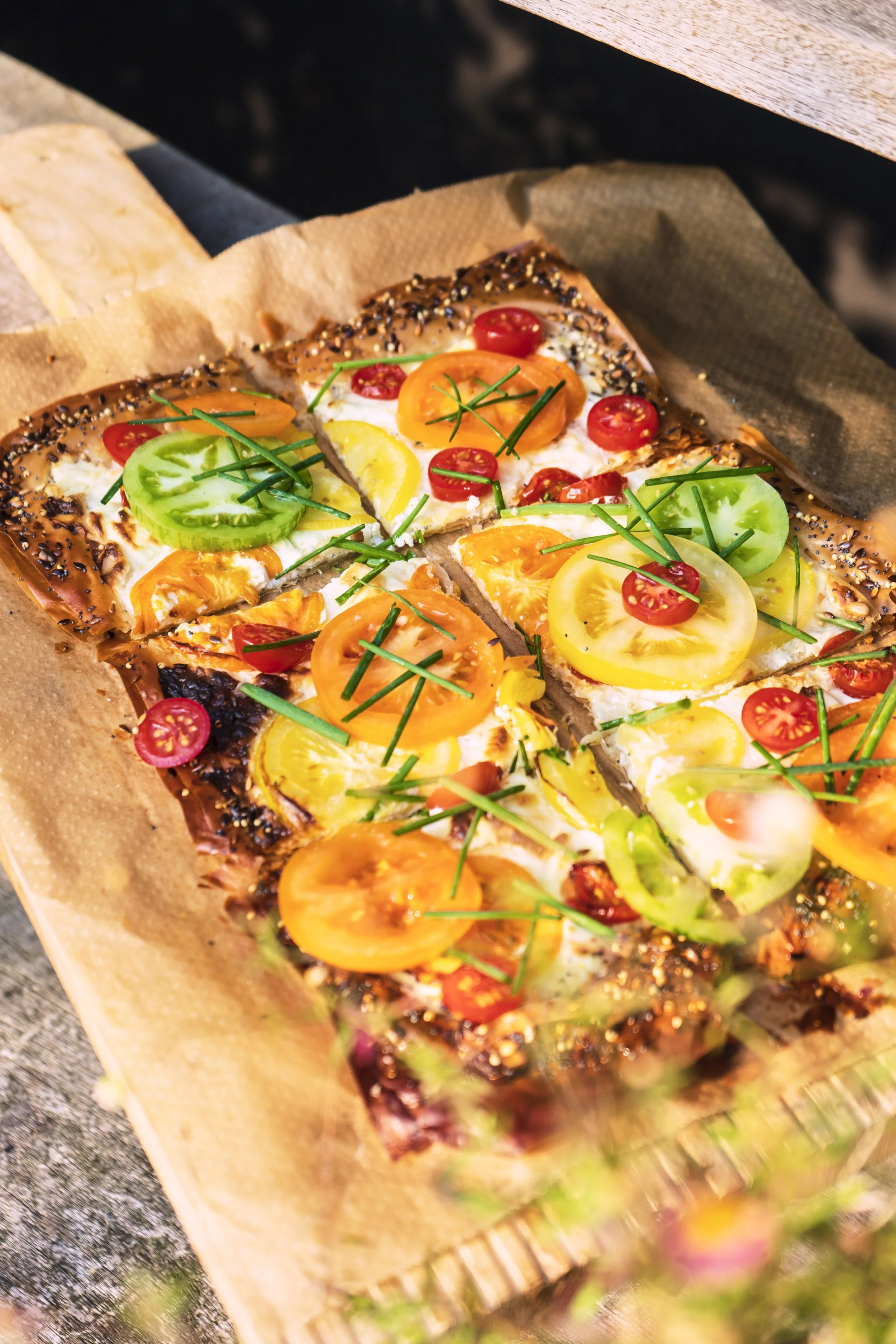 Hartige taart met tomaten en groene kruiden, geplaatst op een houten snijplank.