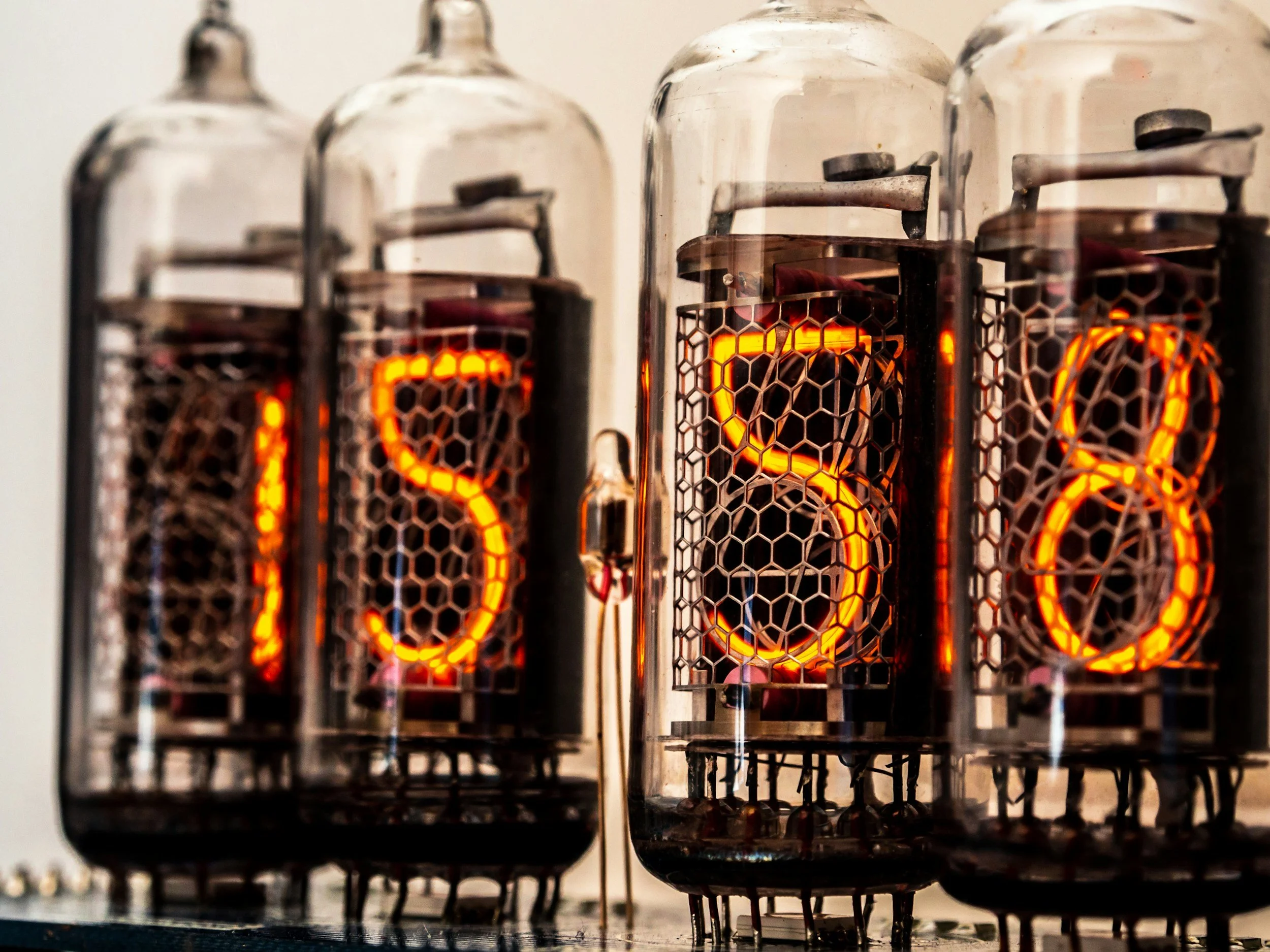 Close-up of vintage vacuum tubes with glowing filaments, arranged on a surface.