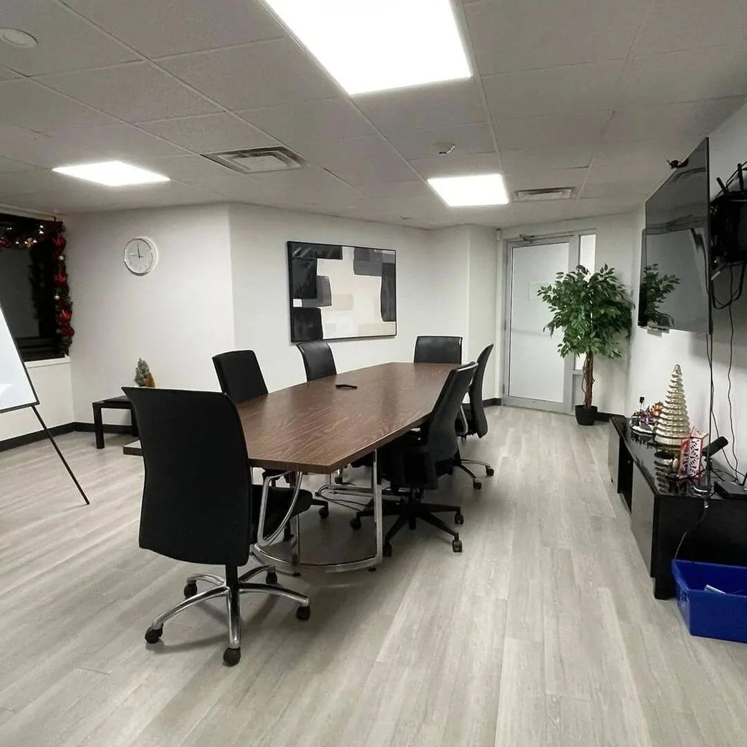 Empty conference room in an office with a large table and six black chairs.