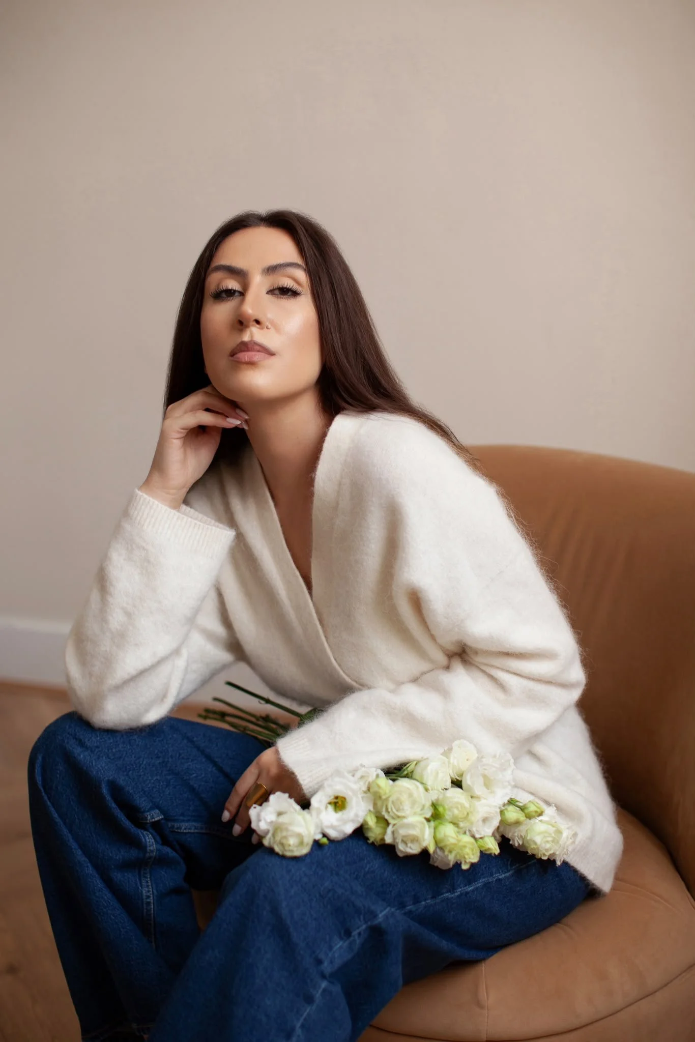 Oana Barabasa, founder of Feminine Signature, seated with white flowers in an elegant interior.