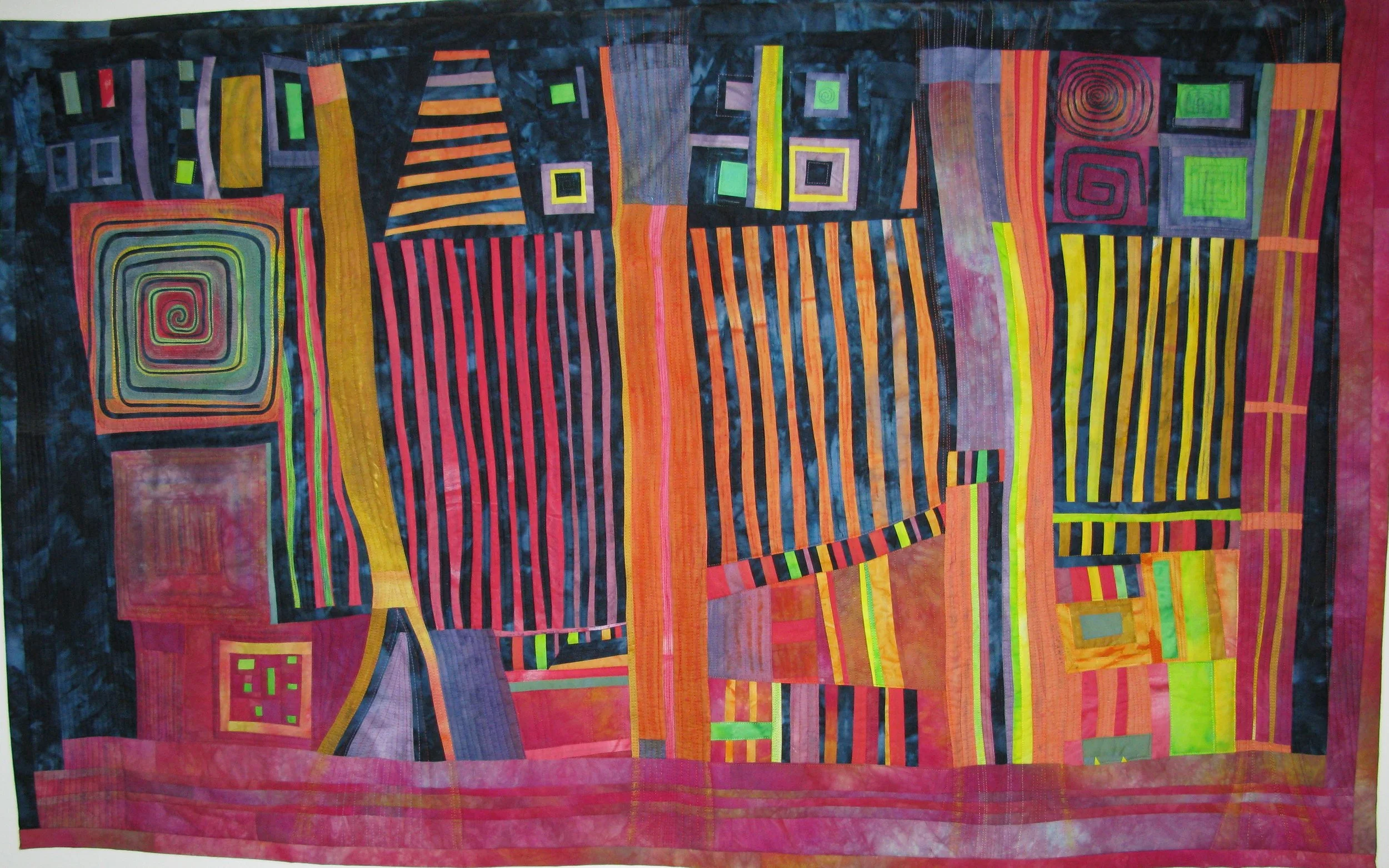 Colorful abstract quilt with geometric patterns, featuring stripes, squares, and swirls in vibrant hues of red, orange, yellow, green, purple, and blue.