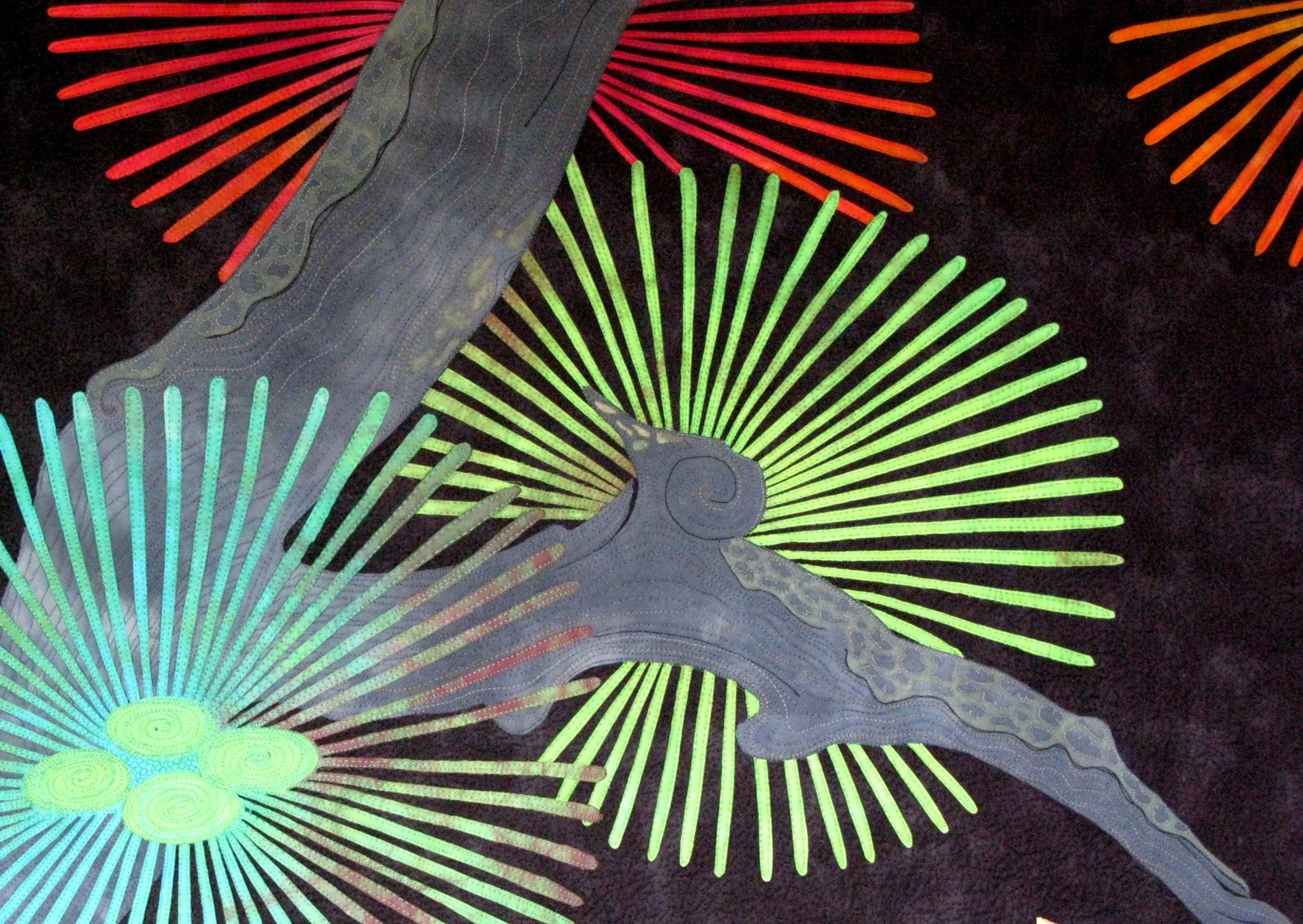Abstract quilt design with colorful radiating patterns on a dark background