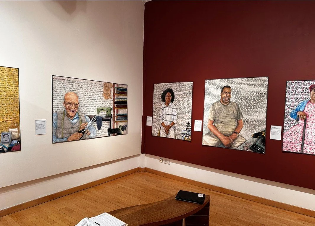 Art gallery with portraits of diverse individuals displayed on white and red walls.