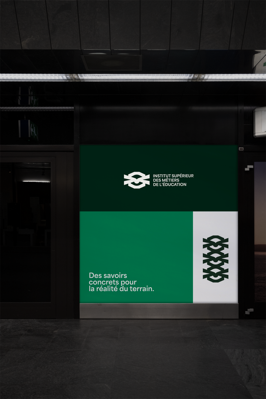 Panneau vert avec le logo de l'Institut Supérieur des Métiers de l'Éducation et la devise 'Des savoirs concrets pour la réalité du terrain'.